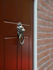 Door knocker in a shape of lion's head on a red door