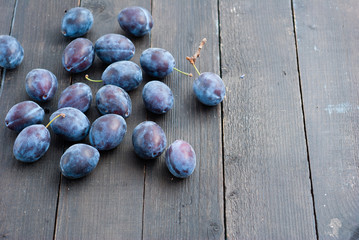 plums on black wood table, front view