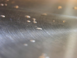drops of condensation on the metal lid of the pan in the glare of the lamp.