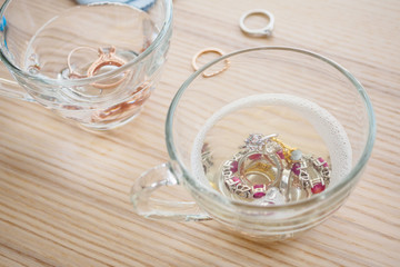 cleaning vintage jewelry diamond ring and bracelet in glass on wood table background