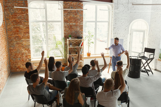 Male speaker giving presentation in hall at university workshop. Audience or conference hall. Rear view of unrecognized participants in audience. Scientific conference event, training. Education