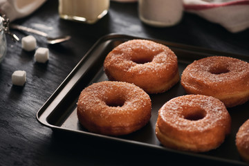 White sugar donuts on a sheet metal tray
