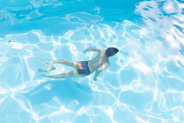 Kid diving in a swimming pool in summer