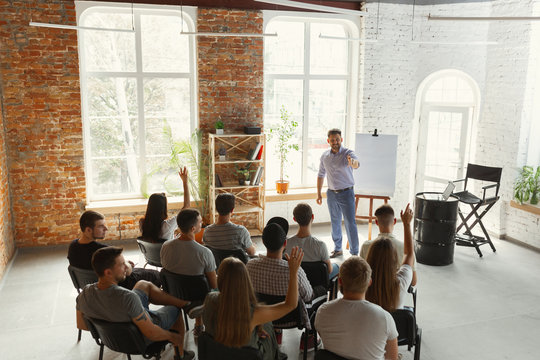 Male speaker giving presentation in hall at university workshop. Audience or conference hall. Rear view of unrecognized participants in audience. Scientific conference event, training. Education