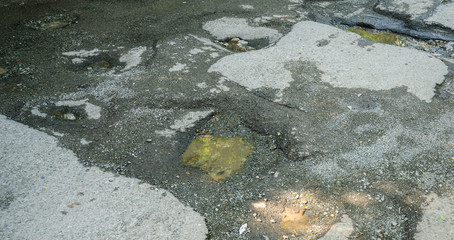 Broken road with potholes after rain.