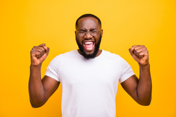 Photo of rejoicing overjoyed joyful black man screaming shouting with his hands showing fists while...