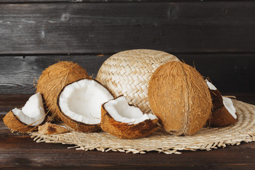 Cracked coconut pieces on dark wooden background