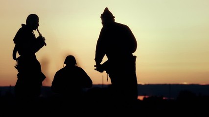 Silhouettes of three musicians. Sunset.