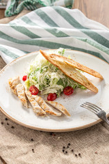 Healthy Grilled Chicken Caesar Salad with parmesan Cheese and Croutons on grey tablecloth
