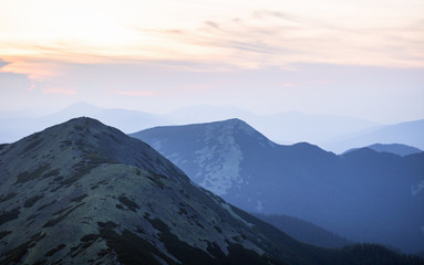 Fototapeta na wymiar mountain range covered with stone scree in the orange and blue twilight light. mountain silhouette