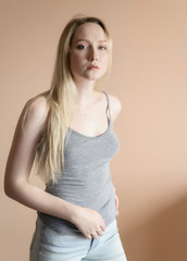 Graceful young woman posing against beige wall.