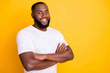 Photo of friendly afro american man standing in front of camera with his hands crossed while isolated with vivid background