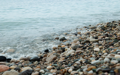 Waves on sea shore. Ripple of water near shoreline. Stone sea shore before the storm. Water movement near the sea.