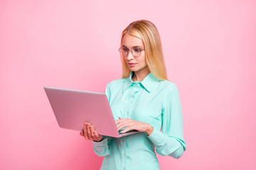 Portait of focused lady with eyewear eyeglasses holding modern technology looking at screen wearing teal turquoise shirt isolated over pink background