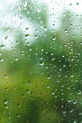 Water drops at rainy day on outside window glass with blurred edges. Raindrops on windowpane in summer day. Rain outside window at summer day.
