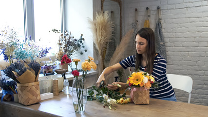 Family flowers business. Florist arranging beautiful composition. Young woman working in lifestyle flower shop. Gardener make bouquet for buyer.