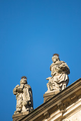 Statues on roof of St. Francis of Assisi church in Prague with blue sky in background