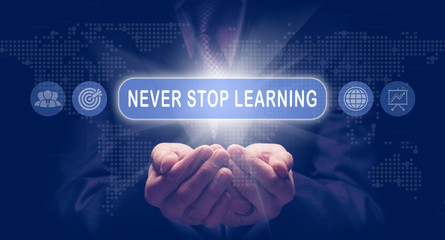 Businessmans cupped hands holding a Never Stop Learning business concept on a computerised display.