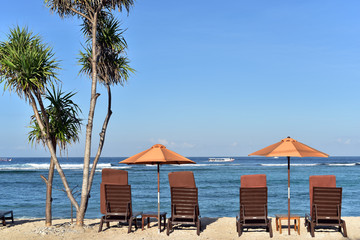 Two umbrellas and beach chairs on empty tropical ocean beach at Nusa Lembongan Island, Bali, Indonesia