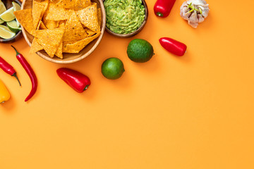 Fototapeta na wymiar top view of crispy nachos, guacamole and spices on orange background with copy space