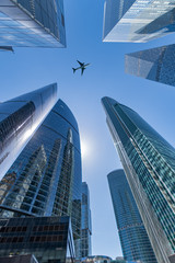 Business center, skyscrapers on sky background and flying plane.