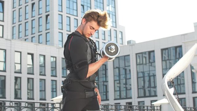 Handsome ambitious bodybuilder in EMS suit. Training on the street. Strength and power concept