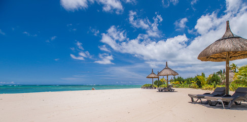Holidays on a tropical island, beach, ocean, palm trees, umbrellas, deck chairs. Mauritius 2018.