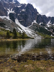 Hiking in Tatra National Park, Poland, in May. Beautiful panoramic view on rocky and snowy mountains, and famous mountains lake Morskie Oko (Sea Eye)