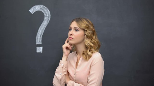 Girl contemplating near question sign on blackboard, solution of complex task