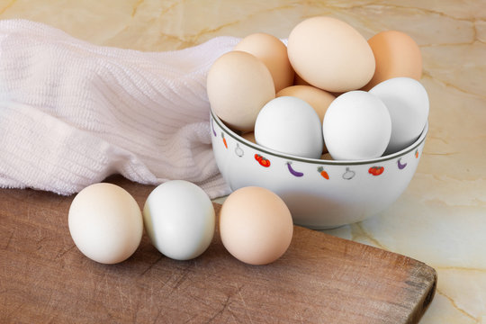 Huevos en una tabla de madera y huevos en un bol y un trapo de cocina