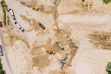 Aerial view of sand quarry with trucks and bulldozers. Heavy bulldozer loading  sand,