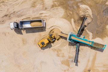 Aerial view of sand quarry with trucks and bulldozers. Heavy bulldozer loading  sand, © netsay