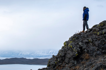 Fototapeta premium Happy man standing on cliff, man looking at landscape view