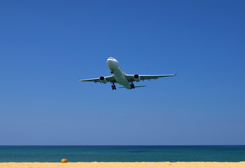 Fototapeta premium Commercial plane landing at phuket on blue sky background, travel concept and business transportation idea