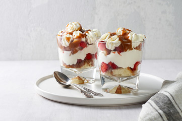 Layered dessert Trifle with vanilla cake, whipped cream, salted caramel and fresh strawberry