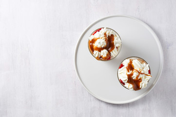 Fototapeta na wymiar Layered dessert Trifle with vanilla cake, whipped cream, salted caramel and fresh strawberry