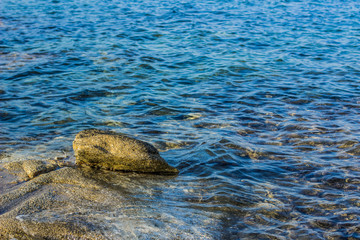 wet stone in blue wavy water simple nature scenic landscape photography with empty space  