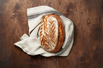 Freshly baked Artisan sourdough bread loaves with kitchen towel on dark wooden background