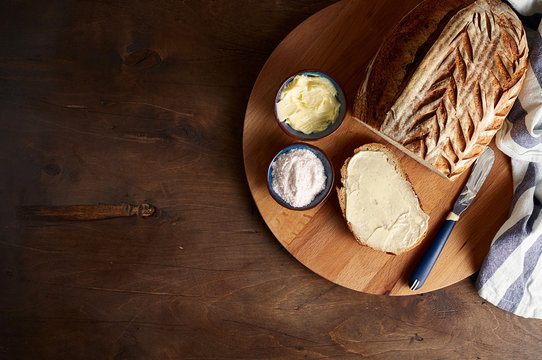 Artisan sourdough sliced toast bread with butter and pink himalayan salt on cutting board