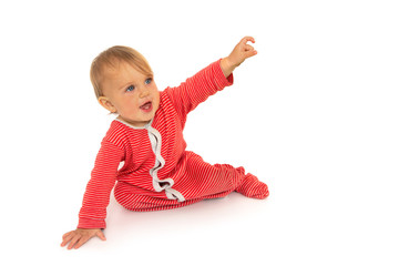 Adorable blue eyed baby with in red romper crawling on all fours and pointing hand and looking away in surprise on white background