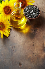 Glass bottle of sunflower oil with seeds and flowers. Close up top view with copy space