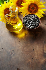 Glass bottle of sunflower oil with seeds and flowers. Close up top view with copy space