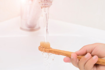 Children's hands wash a toothbrush in the bathroom