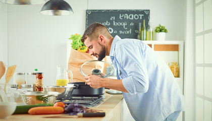 Smiling and confident chef standing in a large kitchen tasting