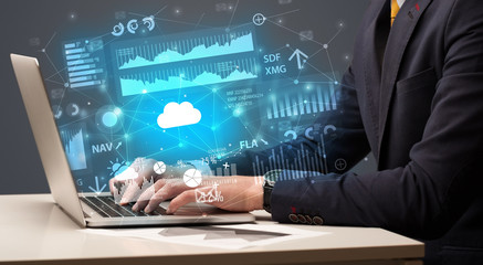 Businessman hand typing on laptop with reports and graphs concept around