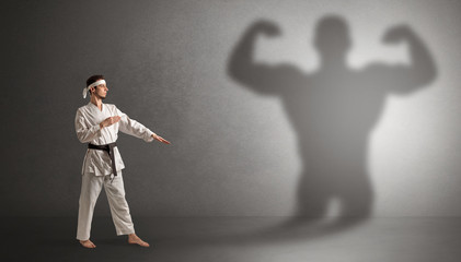 Young karate man fighting with a big black scary shadow