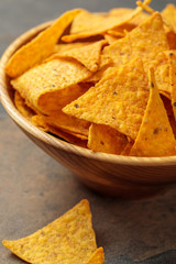 close up view of Mexican nachos in wooden bowl on stone table
