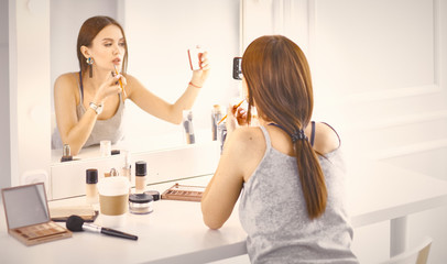 Amazing young woman doing her makeup in front of mirror. Portra