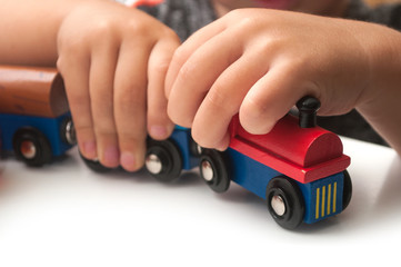 Fototapeta premium Closeup of hand of kid playing with wooden train on white background