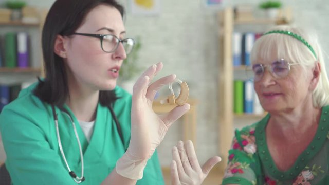 Doctor audiologist tells an elderly woman about the hearing aid
